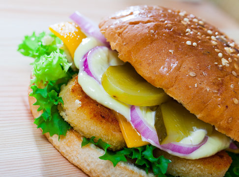 Image of burger with chicken cutlet, cucumber, lettuce and onion
