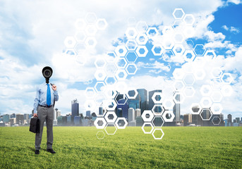 Camera headed man standing on green grass against modern cityscape