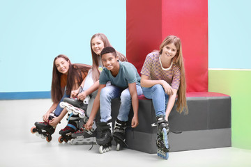 Group of teenagers putting on roller skates indoors
