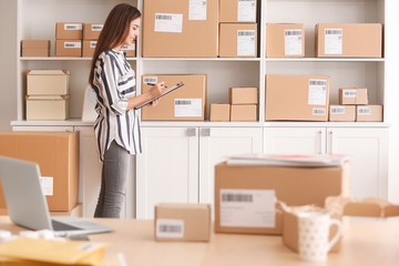 Young woman preparing parcels for shipment to client in home office