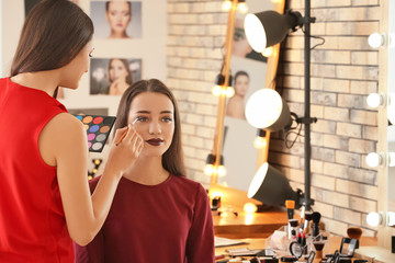 Professional makeup artist working with client in salon