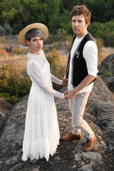 Happy newlyweds standing on rock outdoors