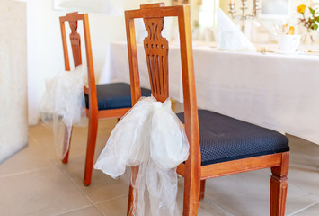 zwei geschmückte Stühle an Hochzeitstisch
