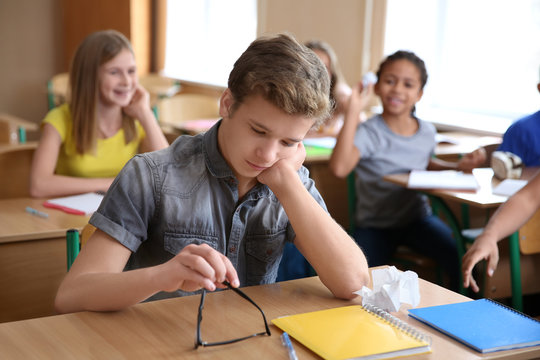 Children bullying teenage boy in classroom