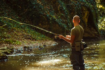 A fisherman fishing with fly fishing in the flowing stream