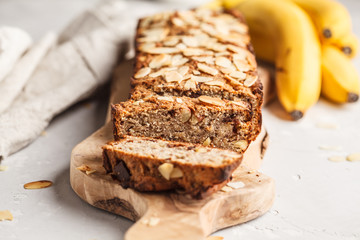 Homemade vegan banana bread with almonds and chocolate, white background.
