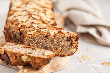 Homemade vegan banana bread with almonds and chocolate, white background.