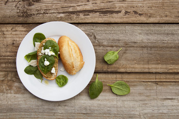 Healthy snack. Bun or bread with pesto pasta and basil leaves. Rustic wooden table, top view.