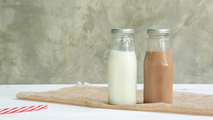 Milk and chocolate milk on a white wooden table.