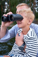  Happy family of father and his son using binoculars together. Outdoors. Exploration and vacation concept