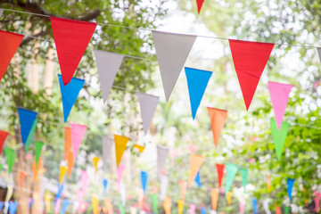 colorful triangle flags hang on white rope in garden for decorative party. - Powered by Adobe