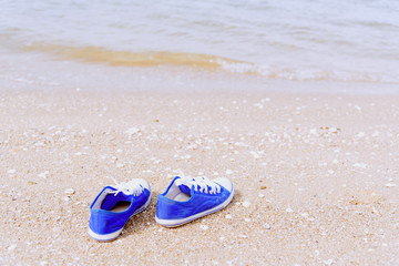 Fototapeta na wymiar Life is journey, Blue sneaker on the beach. Travel Concept.