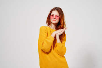 woman joins the palms in a yellow sweater in pink glasses
