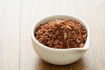 brown rice for healthy white bowl on wood background