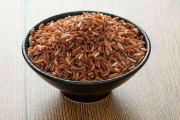brown rice for healthy black bowl on wood background