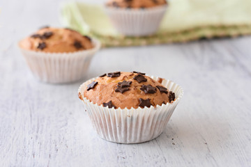 Sweet delicious homemade vanilla muffins whit chocolate chips at white wooden background