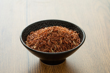 brown rice for healthy black bowl on wood background