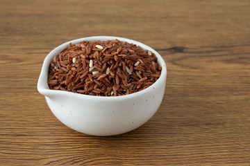 brown rice for healthy white bowl on wood background