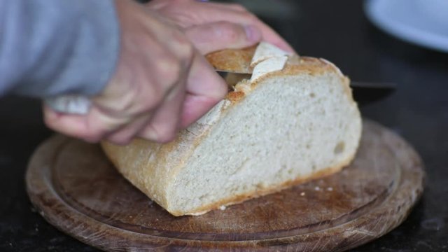 Slicing biological white bread with a bread knife.