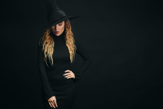 Halloween Sexy Witch portrait. Beautiful young woman in witches hat with long curly red hair and bright lips.  Wide Halloween party art design