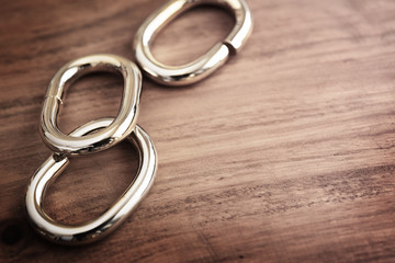 Chain links or chrome metal links on a grungy wooden table. shallow depth of field.