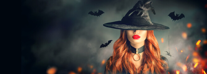 Halloween. Sexy witch portrait. Beautiful young woman in witches hat with long curly red hair over...