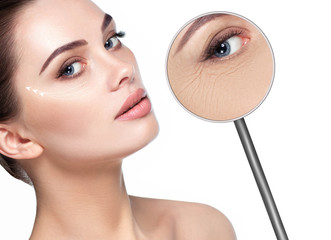 beautiful woman face with lifting arrows on skin and magnifying glass showing aging skin around eyes. Wrinkles around the eyes, the procedure for rejuvenating dry and aging facial skin, mesotherapy - obrazy, fototapety, plakaty