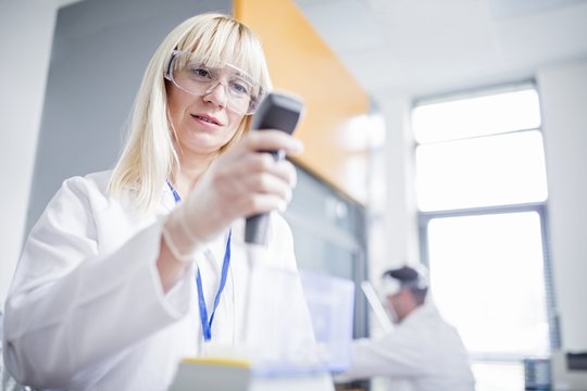 Scientist wearing protective goggles and using device