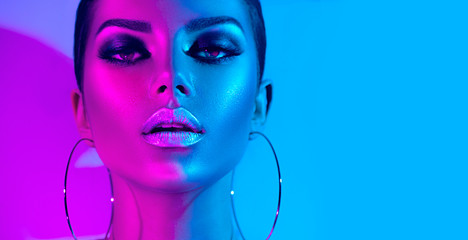 Fashion model brunette woman in colorful bright neon lights posing in studio. Beautiful sexy girl, trendy glowing makeup, metallic silver lips - obrazy, fototapety, plakaty