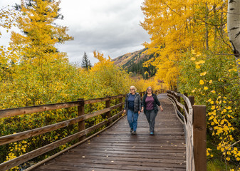 Women hiking along the East of Aspen Trail which Parallels the Roaring River with trees at full...