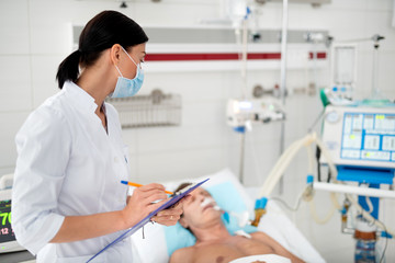 Waist up portrait of female medical worker monitoring condition of sick middle aged man. Gentleman...