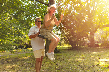 senior couple playing with swing in the garden at sunset
