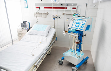 Waiting for patients. Modern and fully equipped recovery room in white tones with bed, mechanical ventilator and digital device for measuring blood pressure