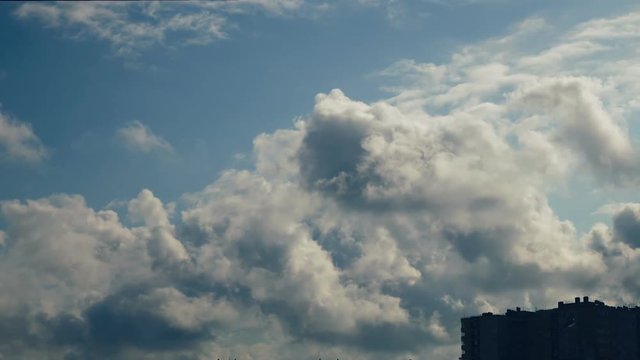 clouds over the house. Clouds drag the blue sky, trees lean from the wind.