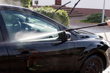 Cleaning the black car, car care concept - Car washing under high pressure water