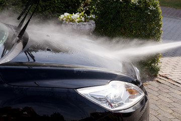 Cleaning the black car, car care concept - Car washing under high pressure water