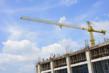 Crane and workers at construction site against blue sky