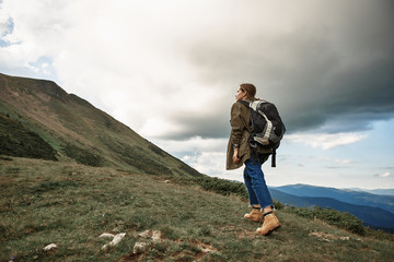 Traveling alone. Active young hiker looking confident while climbing the mountains with big heavy backpack