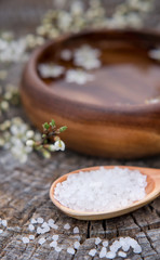 Spa and wellness setting with sea salt, oil essence, flowers and towels on wooden background. Relax and treatment therapy.