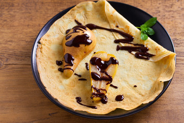 Crepes with baked pear and chocolate. Pancakes with baked pear and chocolate. View from above, top studio shot
