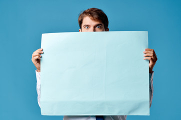 a man holds in front of a blue sheet of paper