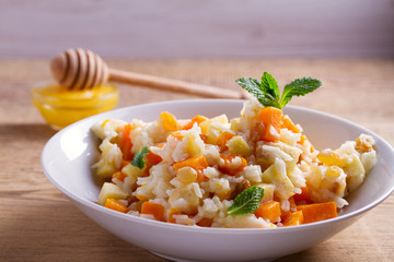 Rice porridge with pumpkin, apples and raisins in white bowl. Vegetarian diet dish of rice and pumpkin. Healthy food. horizontal