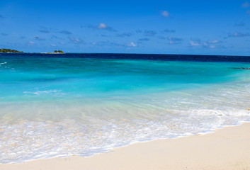 A seascape of pristine beach and deep blue ocean, on a tropical island, in the Maldives.