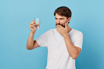 a glass of water in the hand of a man on a blue background