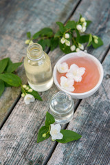 Spa and wellness setting with sea salt, oil essence, jasmin flowers and towels on wooden background. Relax and treatment therapy.
