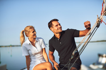 Smiling young couple sailing their yacht on a sunny day