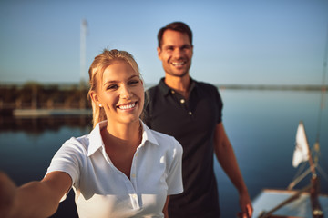 Young couple smiling while standing together on their yacht