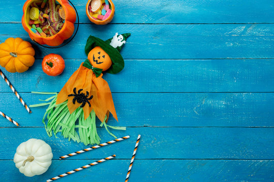Table top view aerial image of decoration Happy Halloween day background concept.Flat lay accessories essential object to party the pumpkin  & cute doll on blue wooden.Space for creative design.