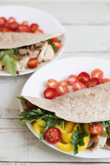 Healthy whole wheat wrap with chicken breast, mushroom, cherry tomatoes, bell pepper, parsley and arugula leaves. Healthy and balanced snack