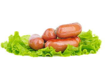 Grilled sausages on green lettuce leaf isolated on the white background